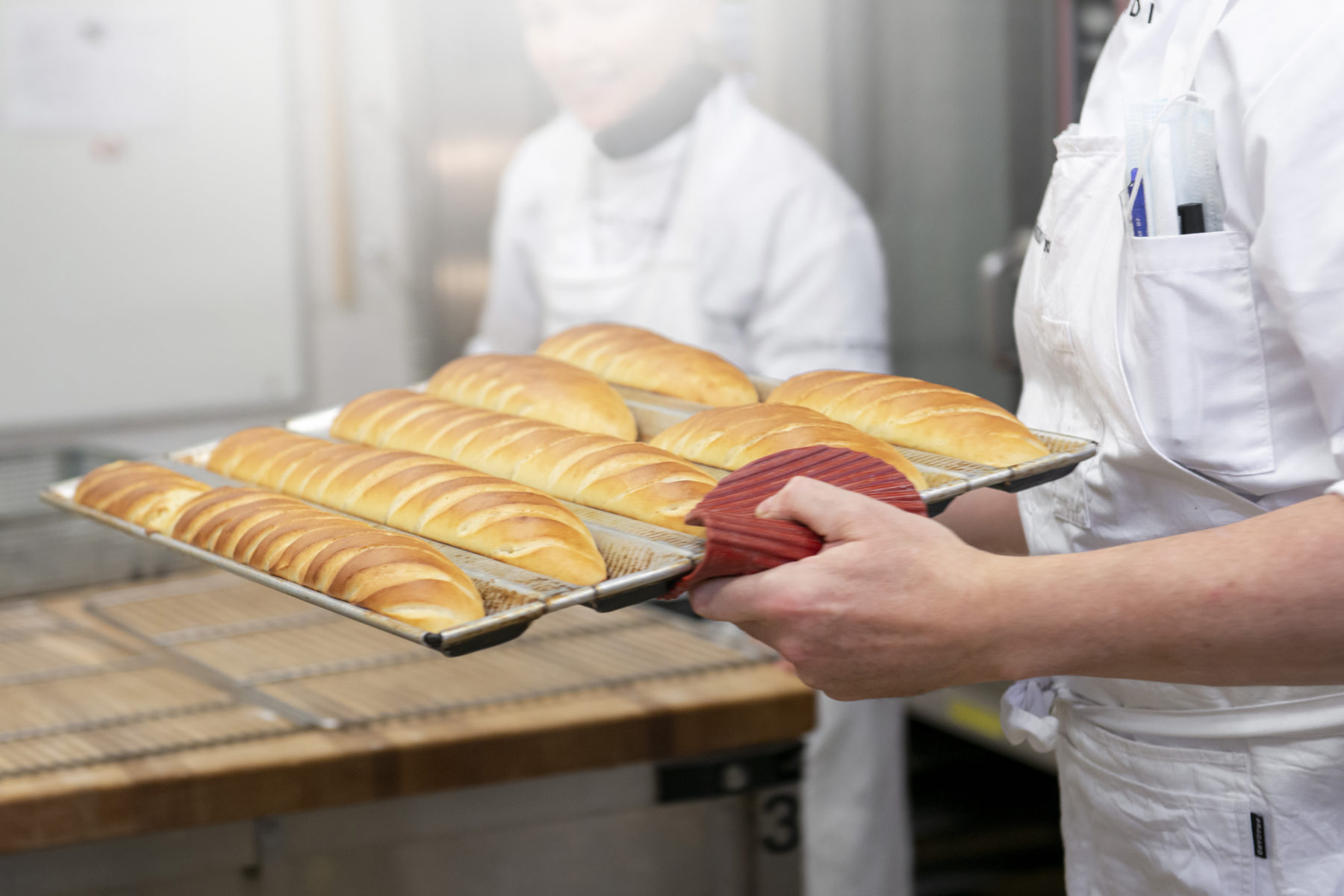 A bakery student scoring baguettes